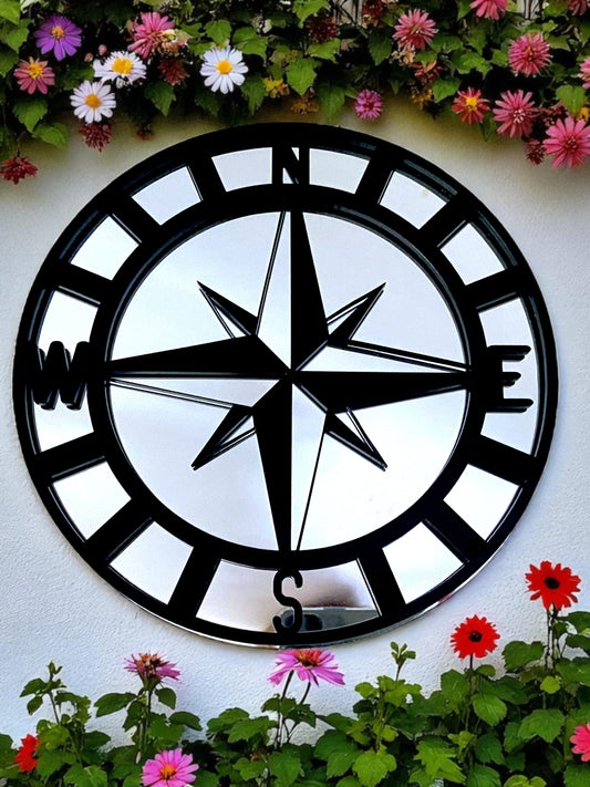 Round black and mirror compass garden mirror with cardinal points N, E, S, W, mounted outdoors.