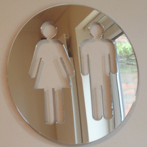 Round mirrored acrylic toilet sign with cutout male and female figures.