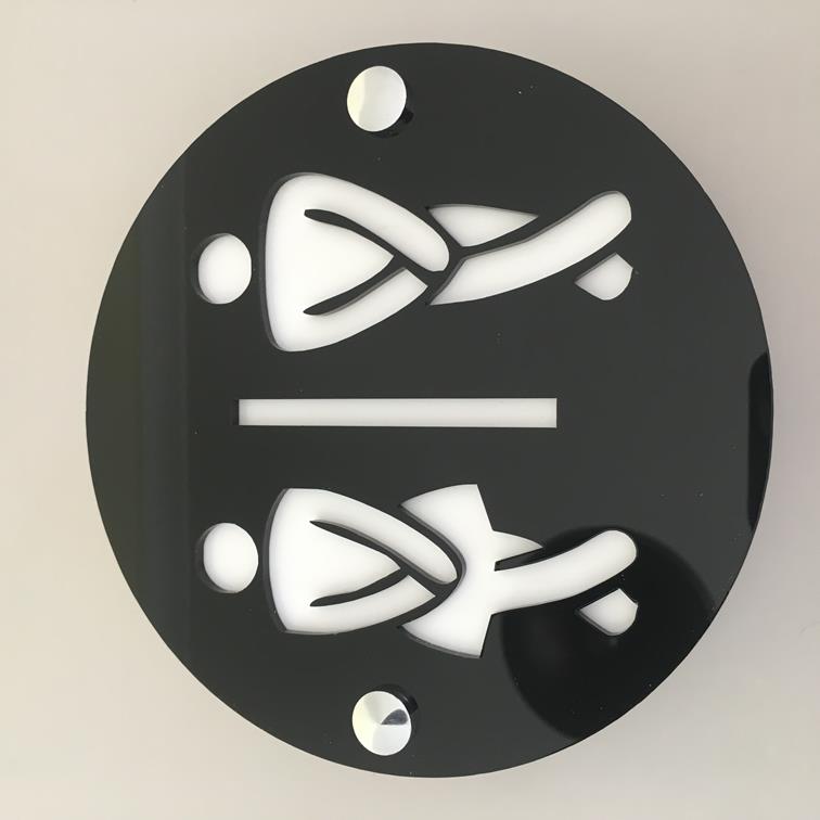 Round black acrylic toilet sign with mirrored cut-out figures of two people with crossed legs and a dividing line.