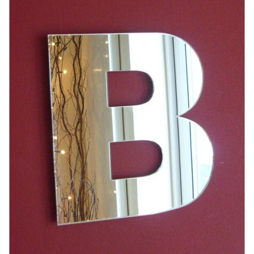 A contemporary letter B-shaped wall mirror mounted on a dark red wall.