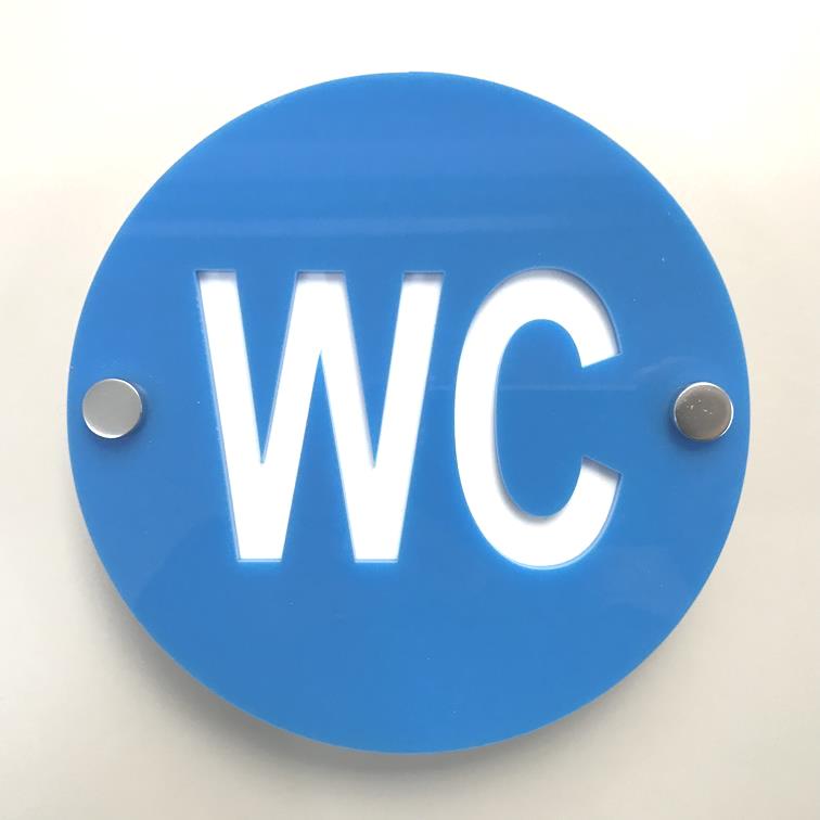 Round blue acrylic toilet sign with cut-out white WC letters and two silver standoffs.