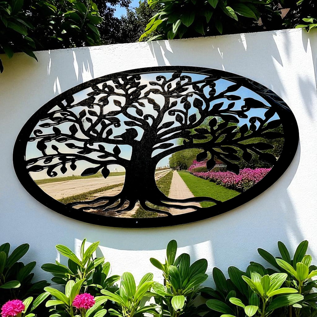 An oval mirror with a black metal Tree of Life overlay, mounted on a white garden wall.