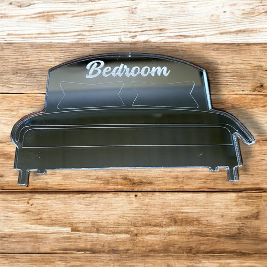 Bed-shaped engraved mirror with "Bedroom" text and pillow outlines on wood.