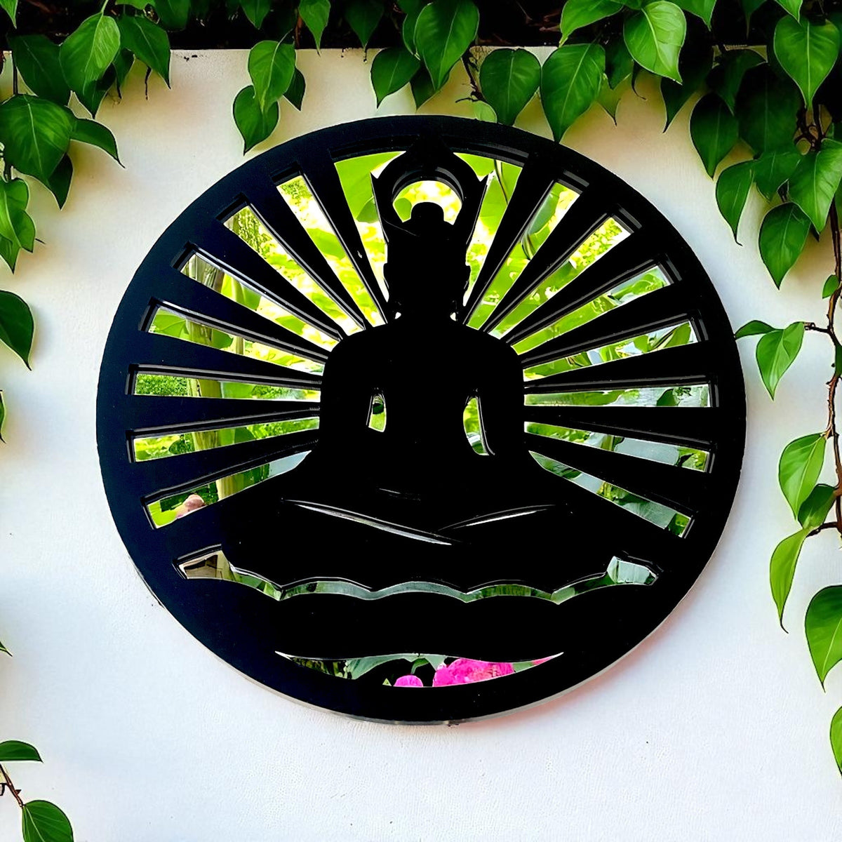 A round black metal garden mirror featuring a meditating Buddha silhouette with radiating sun rays.