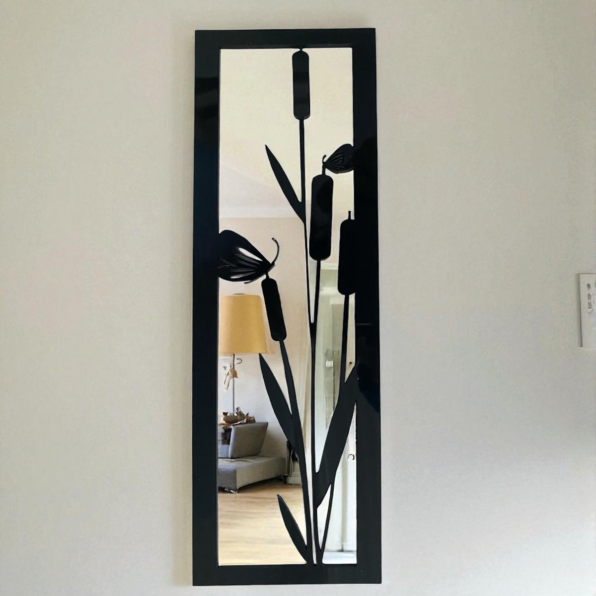 Rectangular black metal framed mirror featuring a bulrush and butterfly design overlay.