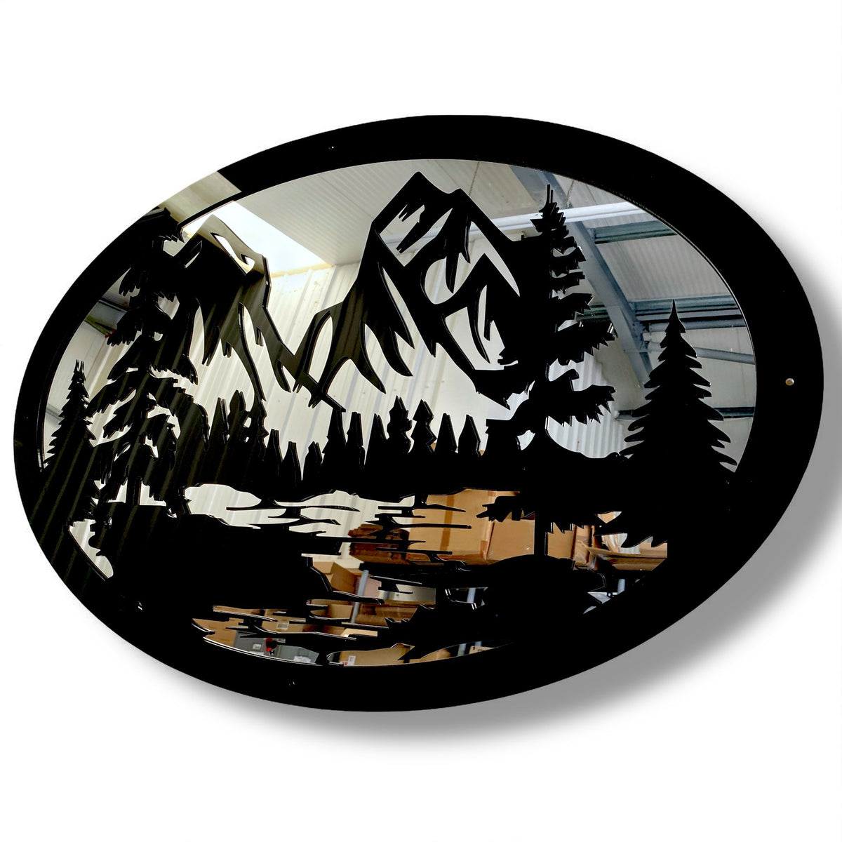 Oval black metal garden mirror featuring a laser-cut mountain range and pine trees silhouette.