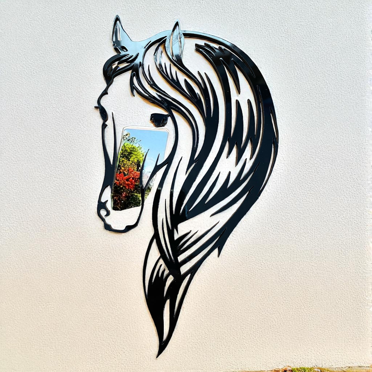Black metal horse head garden mirror mounted on a light wall, featuring a reflective cheek insert.