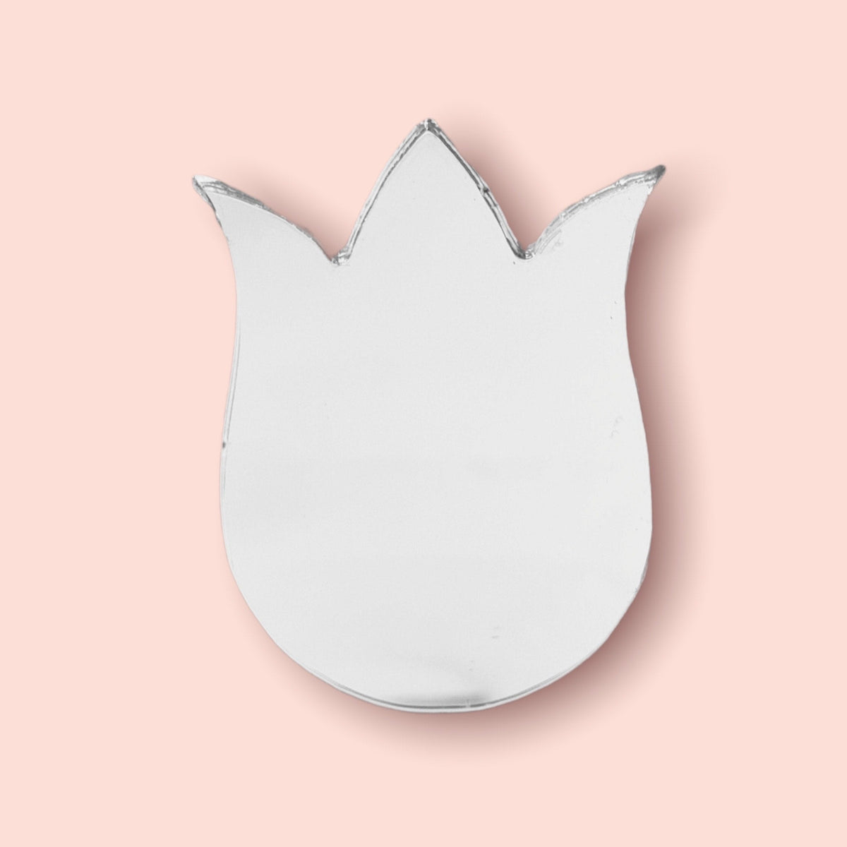 A tulip flower-shaped wall mirror with a reflective glass surface against a solid light pink background.