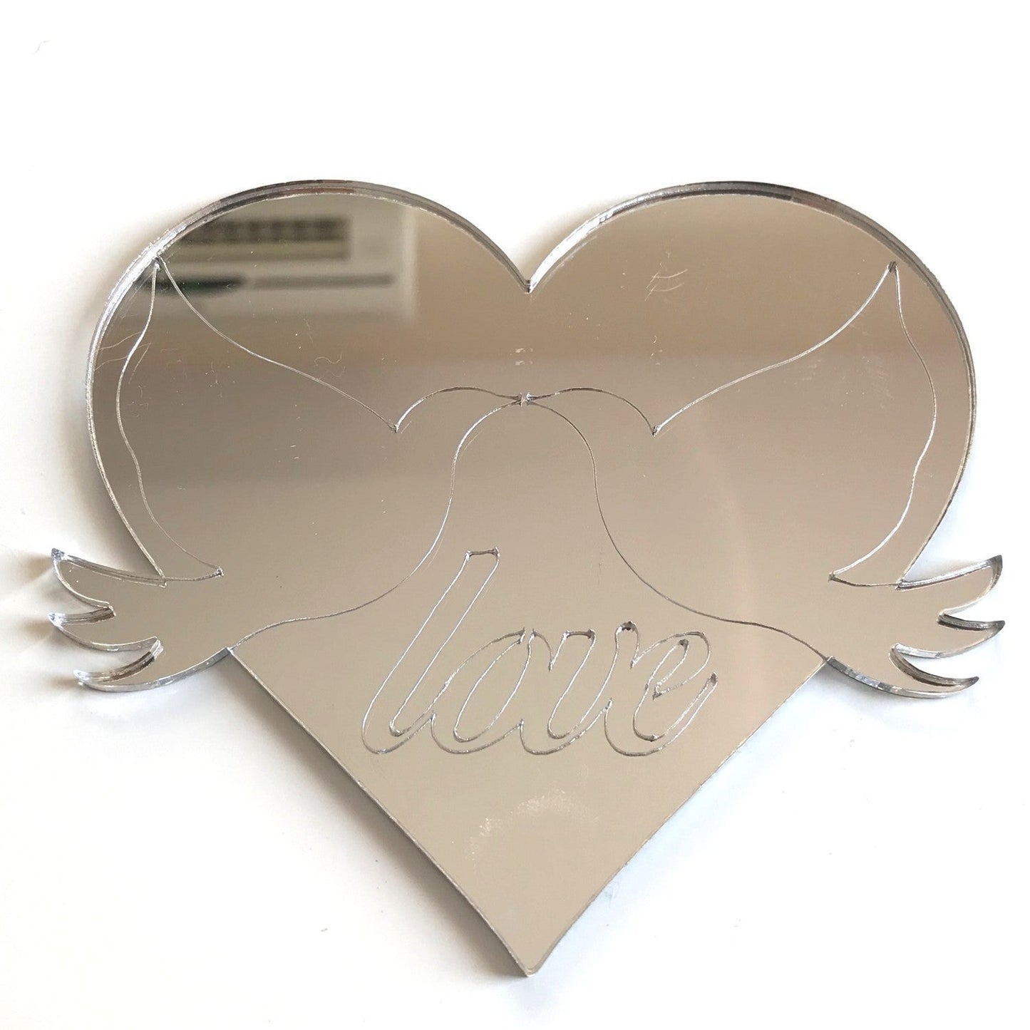 Heart-shaped reflective mirror with etched outlines of two doves and the word love.
