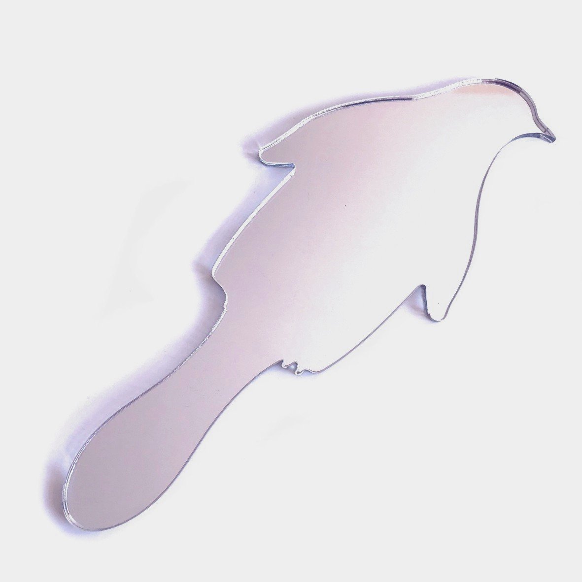 A penguin-shaped handheld mirror with a reflective surface and an integrated handle, set against a plain background.