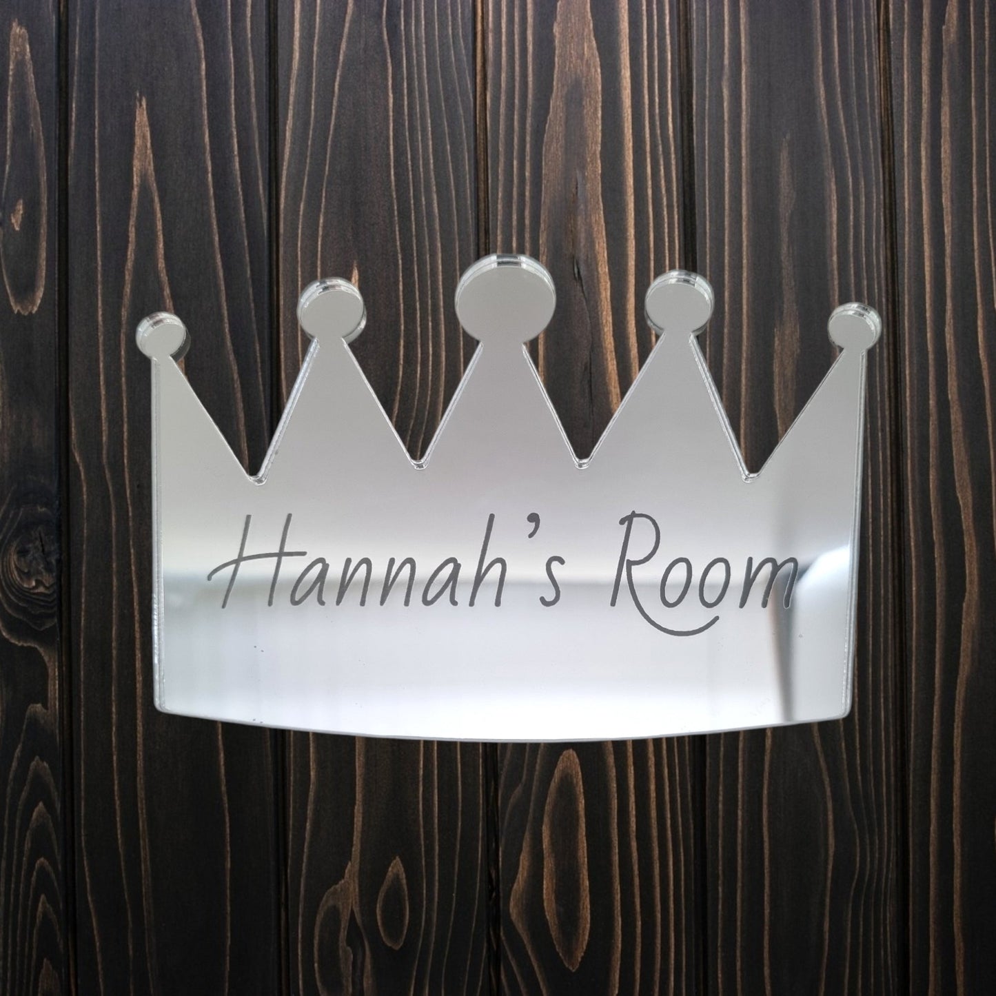 Personalised silver mirrored crown door sign engraved with "Hannah's Room," mounted on wood.