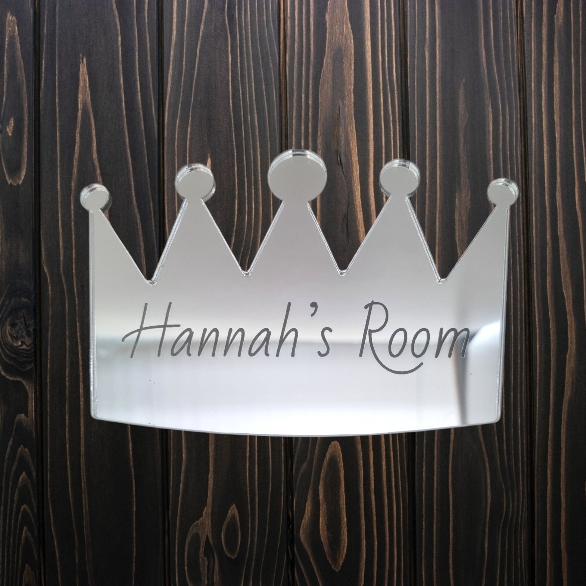 Personalised silver mirrored crown door sign engraved with "Hannah's Room," mounted on wood.