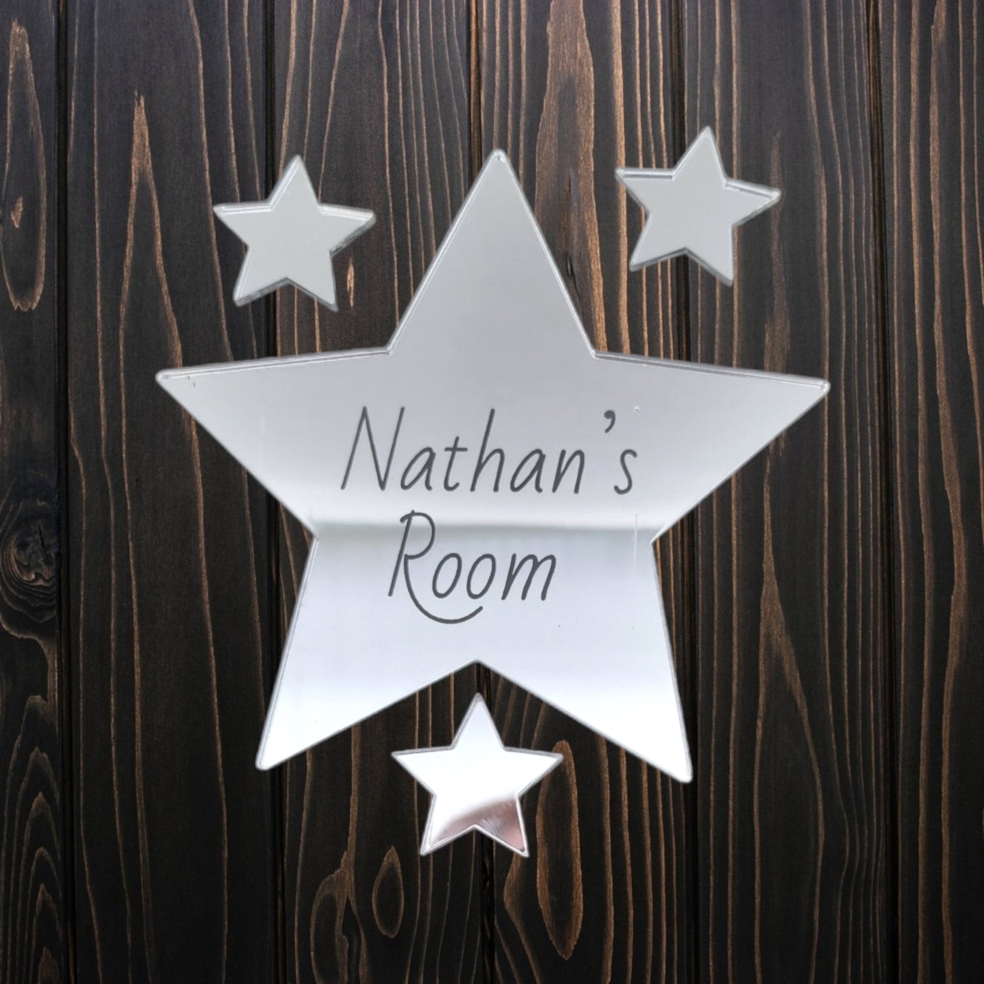 Personalised silver mirrored star door sign engraved with "Nathan's Room" and three smaller stars.