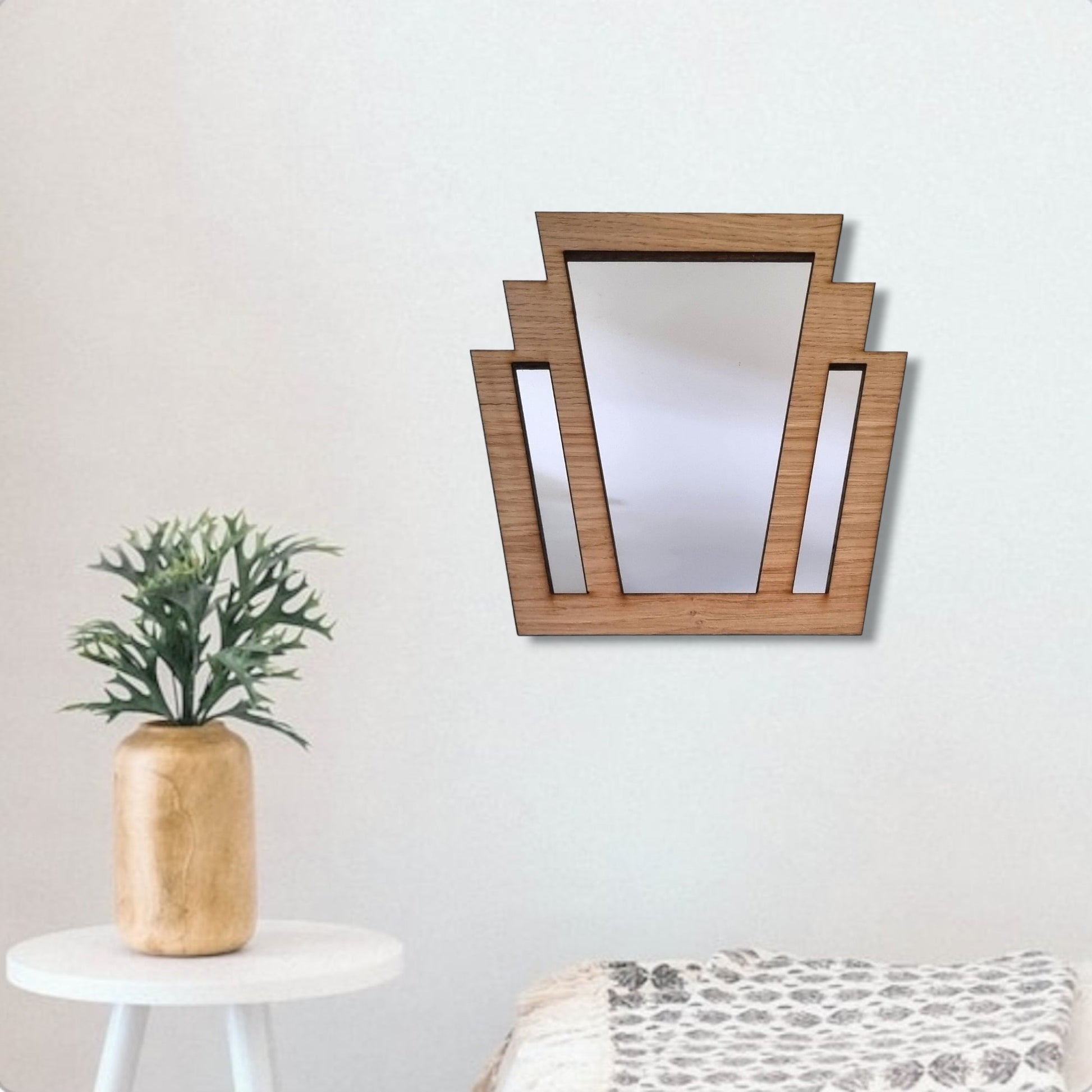 Art Deco style wood-framed fan mirror hanging on a white wall above a small side table and plant.