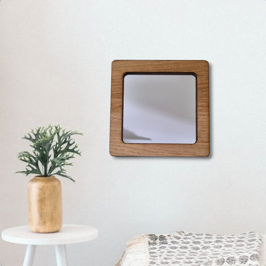 A square wall mirror with a thick brown wooden frame hangs against a plain white wall.