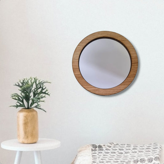 Round mirror with a light brown wood frame hanging on a plain white wall.