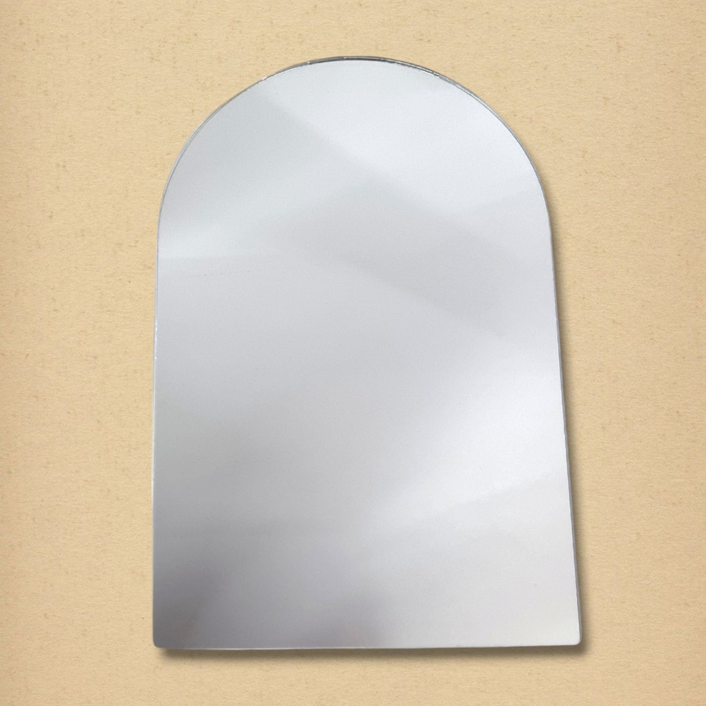 An arch mirror with a flat bottom and rounded top on a tan background.