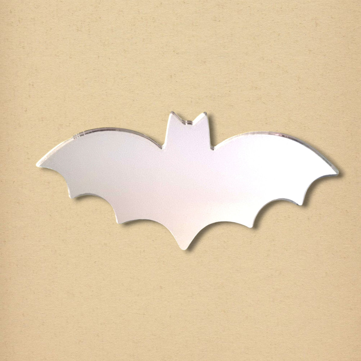 A silver bat-shaped acrylic mirror on a light beige background.