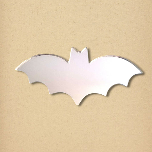 A silver bat-shaped acrylic mirror on a light beige background.