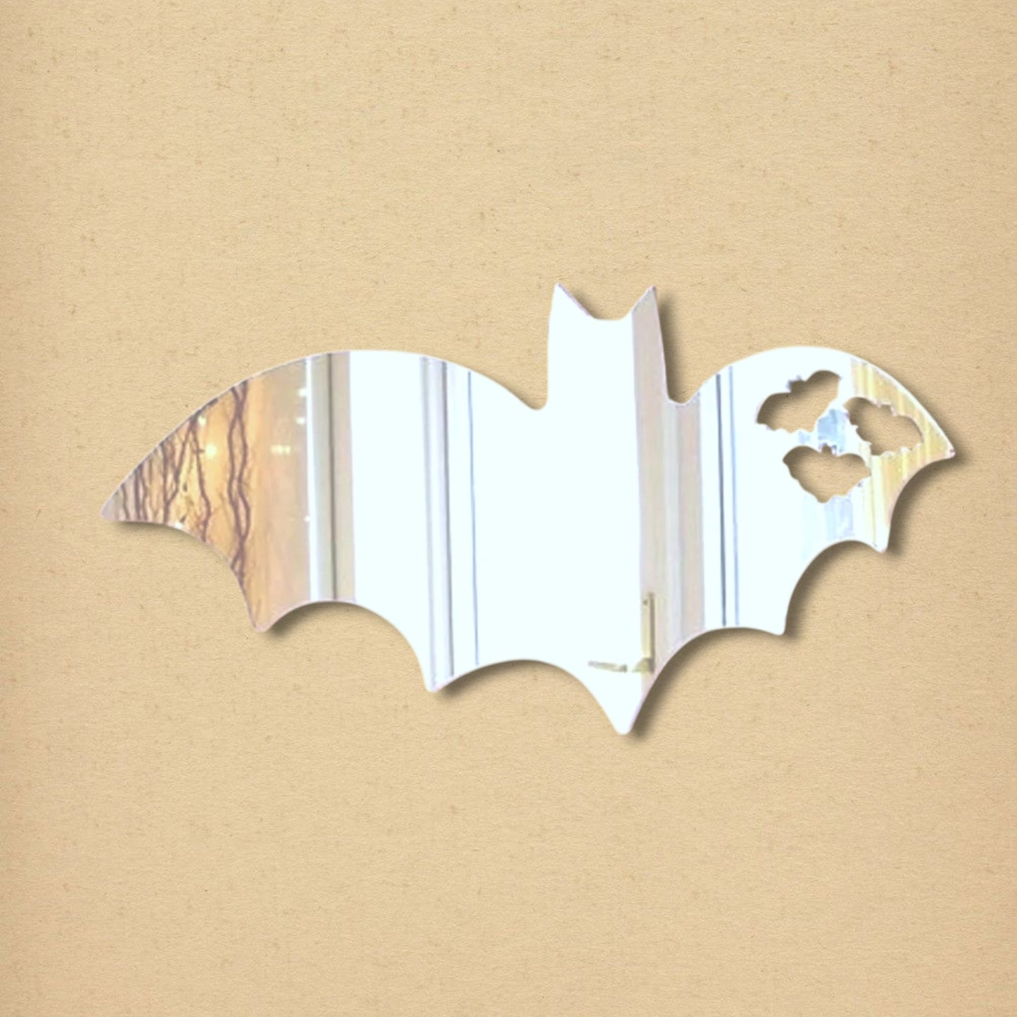 Bat-shaped mirror with three small cutouts resembling bats flying away on the right wing.