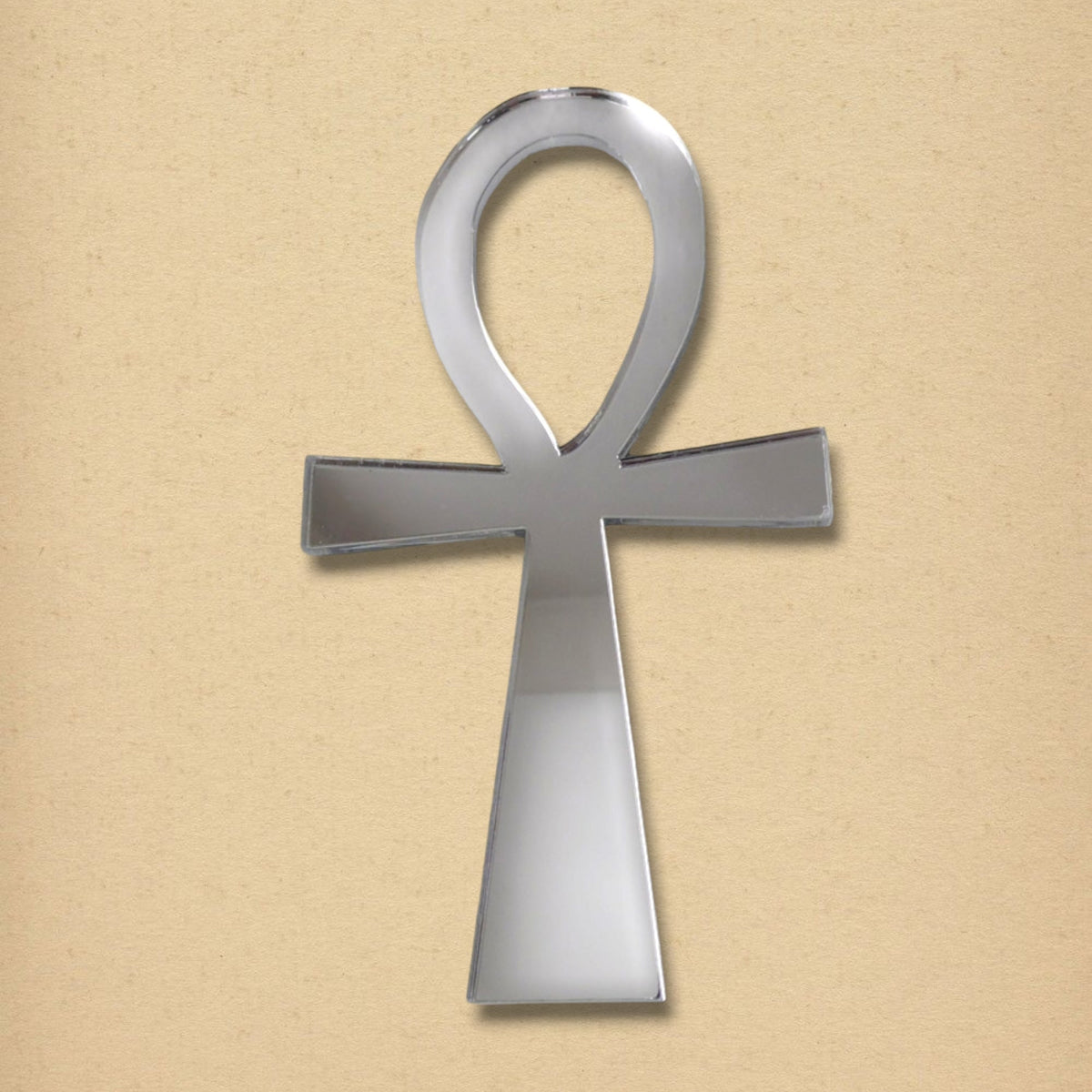 Ankh-shaped silver acrylic mirror against a textured beige background.