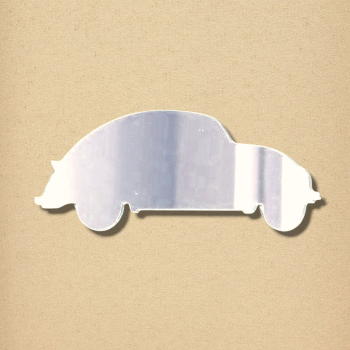 A silver, reflective acrylic mirror shaped like the side profile of a classic car, shown against a neutral beige background.