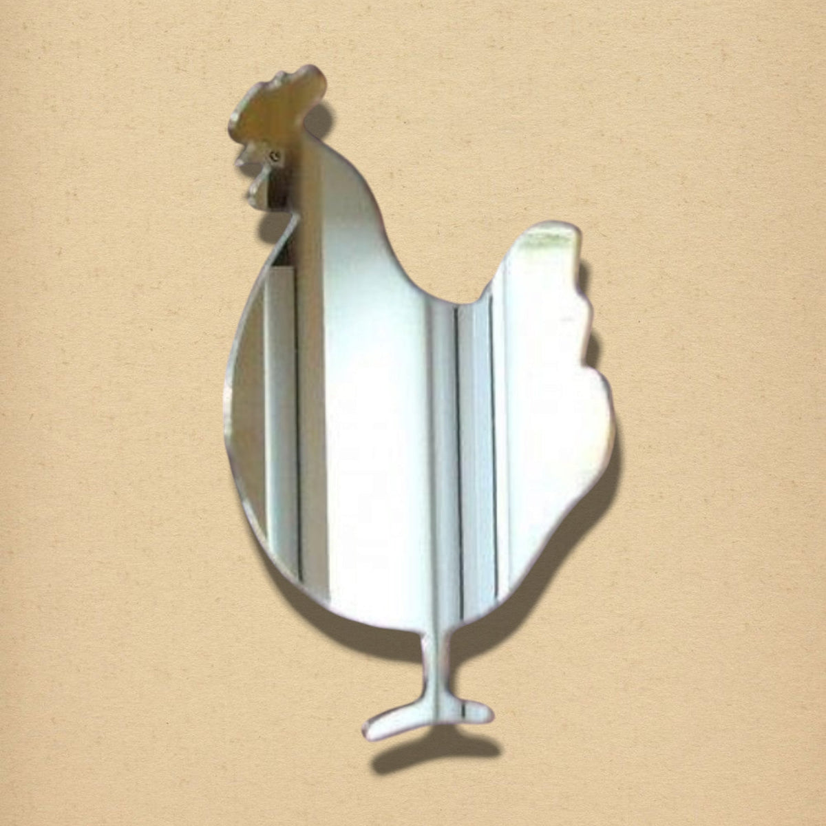 A cockerel-shaped mirror made of reflective glass on a plain beige background.