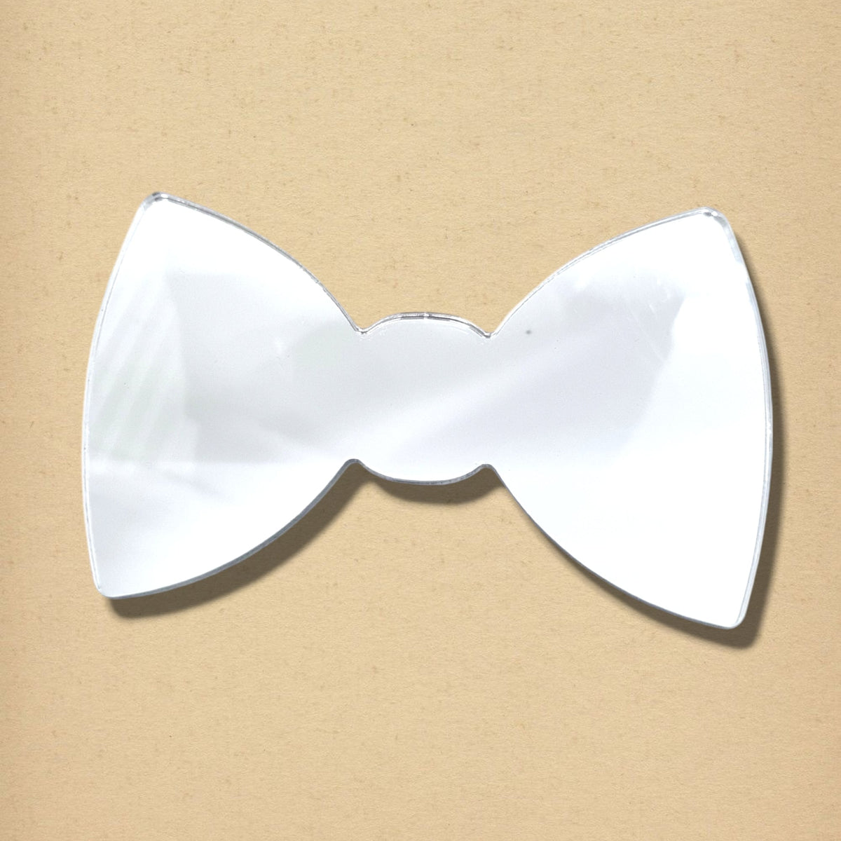 Bow-tie-shaped silver mirror on a light brown background.