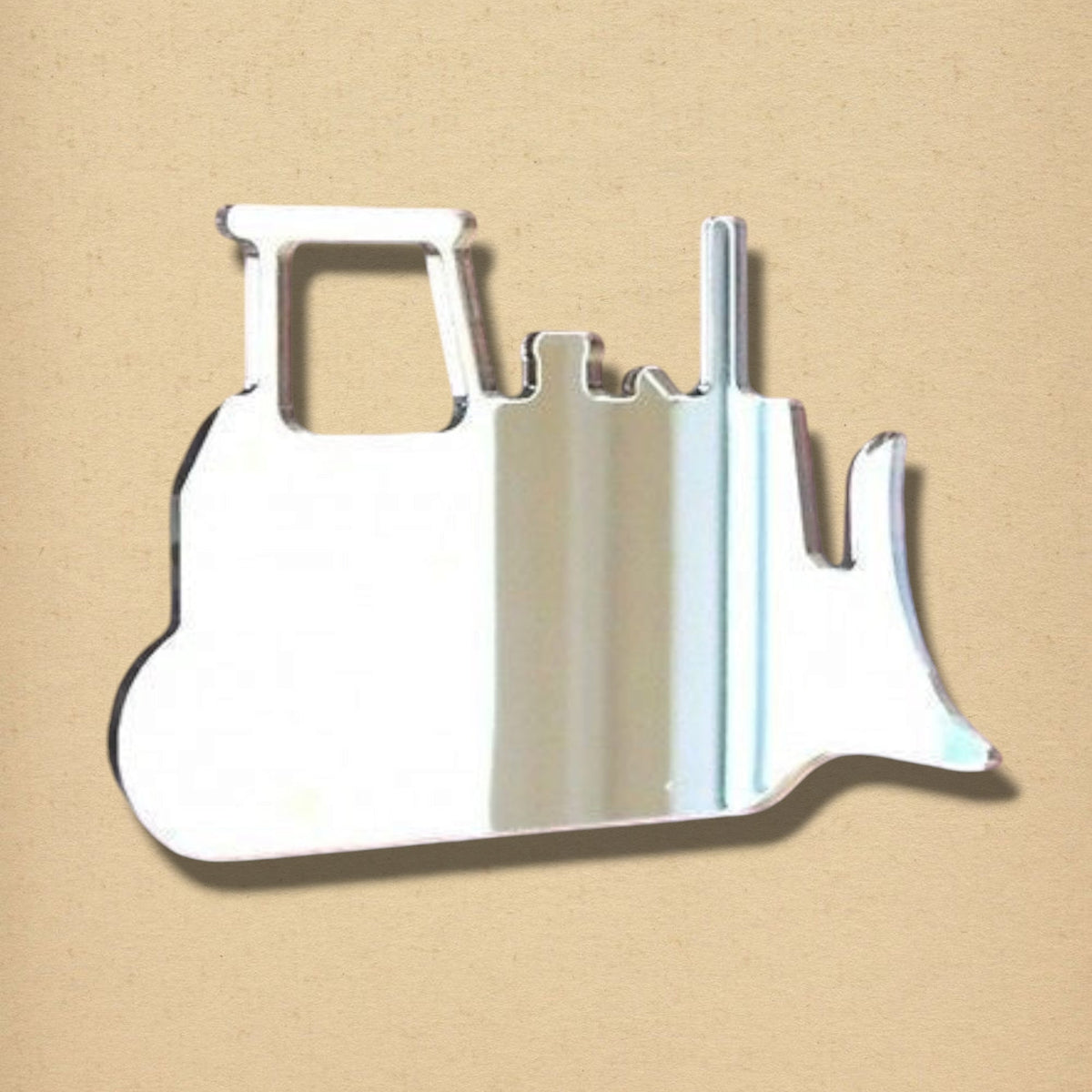 Bulldozer-shaped silver mirror against a beige background.