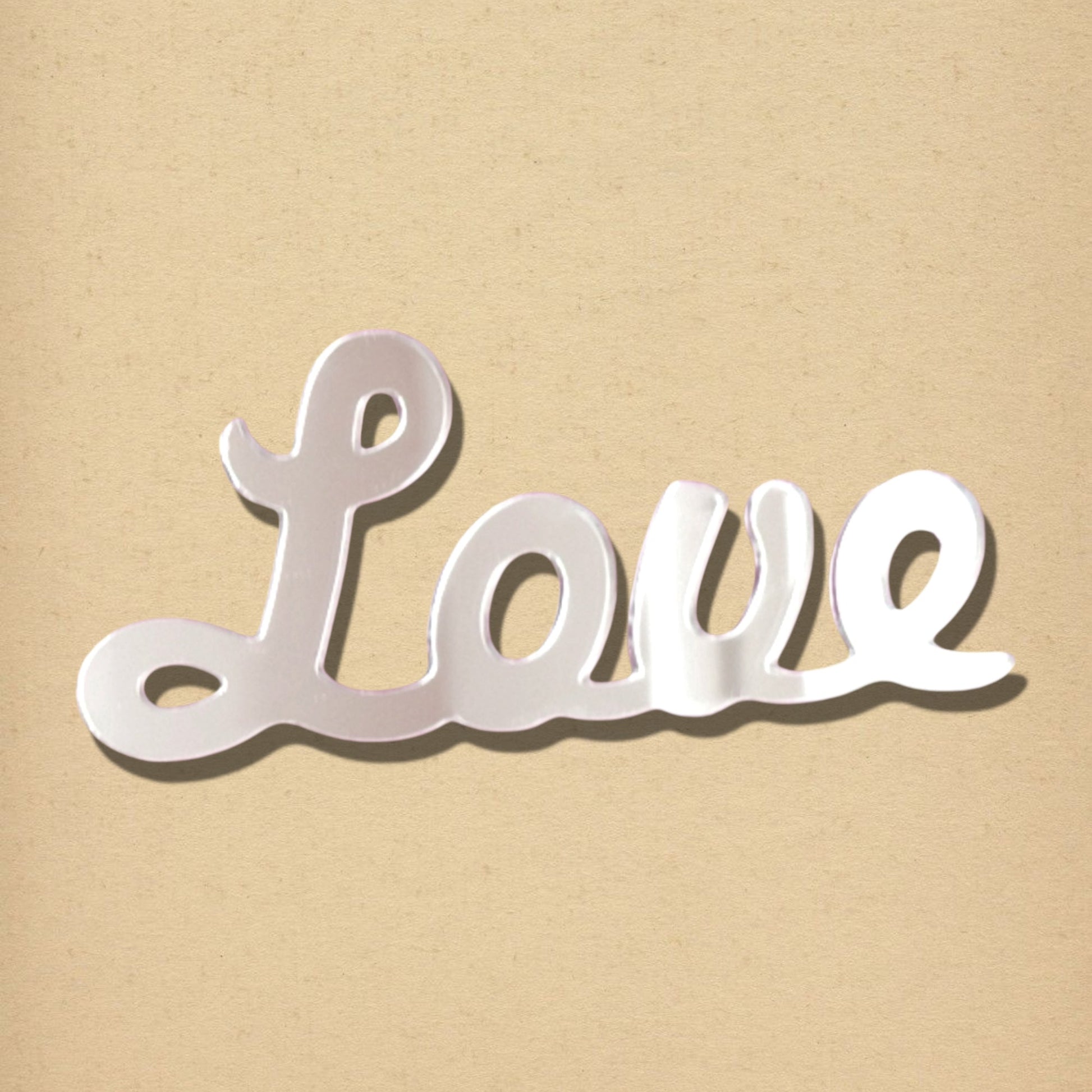 Silver script mirror shaped like the word "Love" on a neutral background.