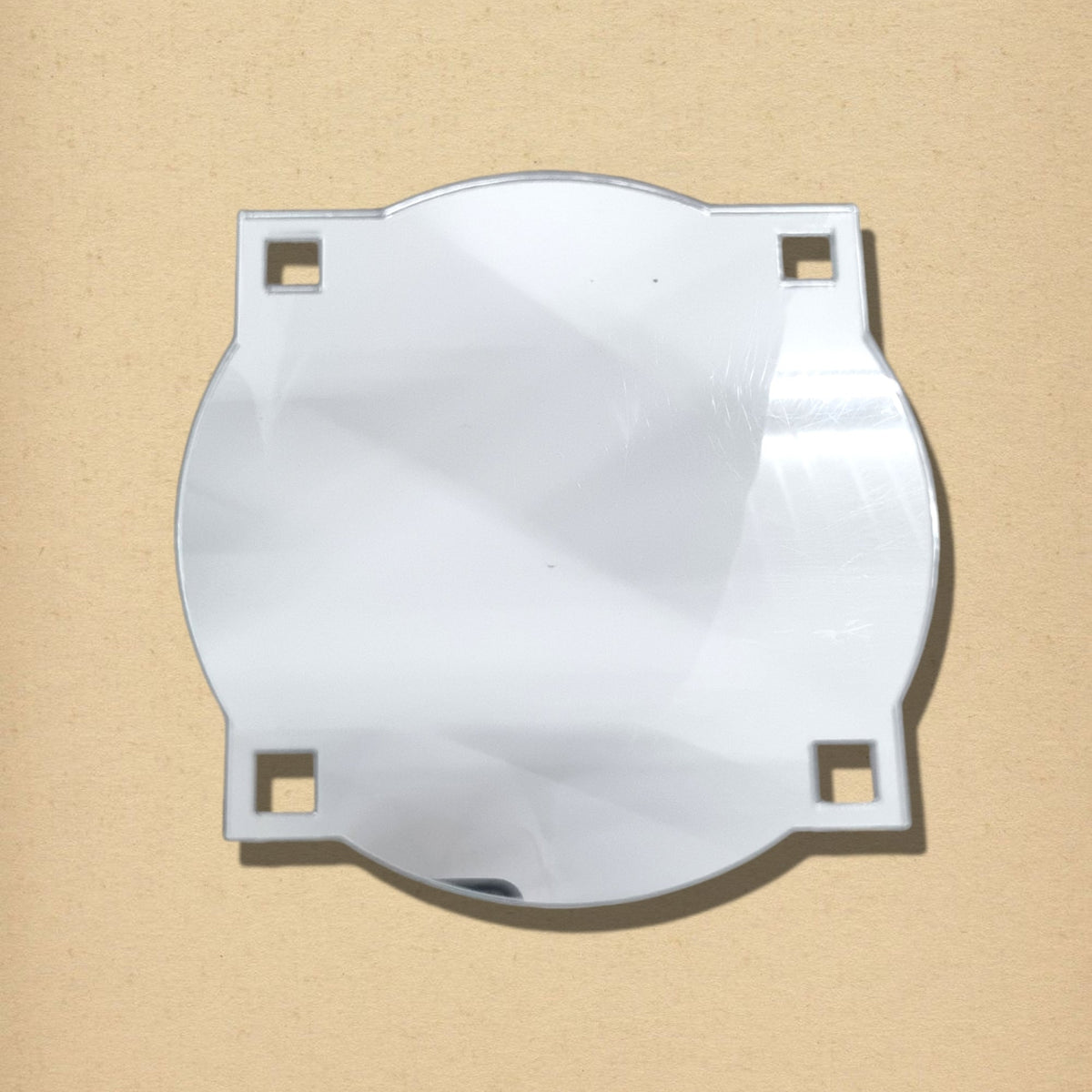 Art Deco round mirror with curved edges and four corner square cutouts against a beige textured background.