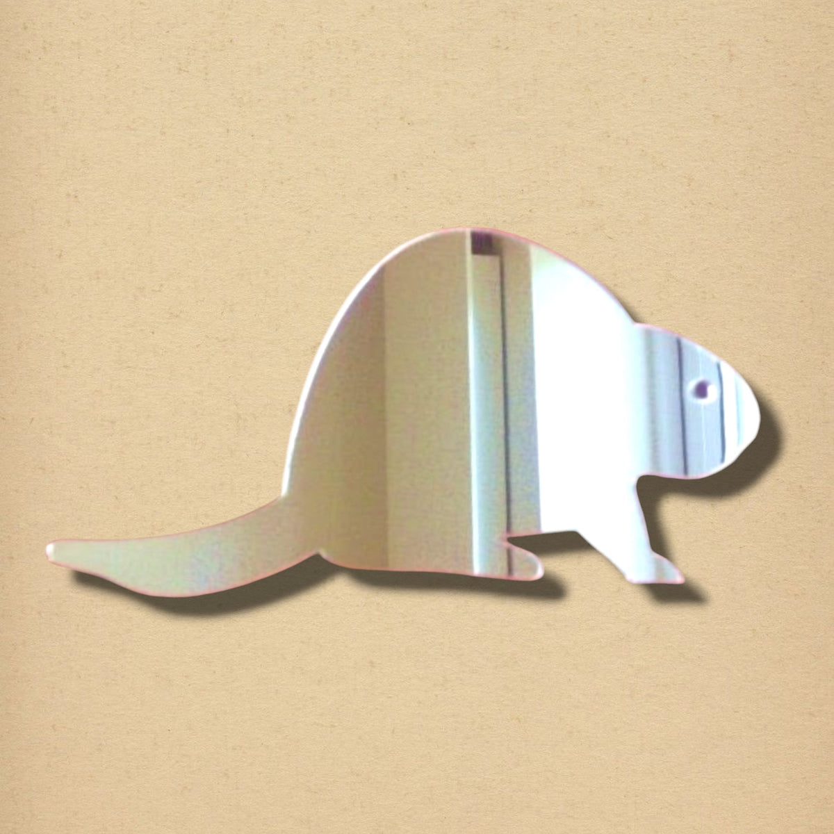 Beaver-shaped wall mirror with a flat tail, short legs, and a small eye detail on a tan background.