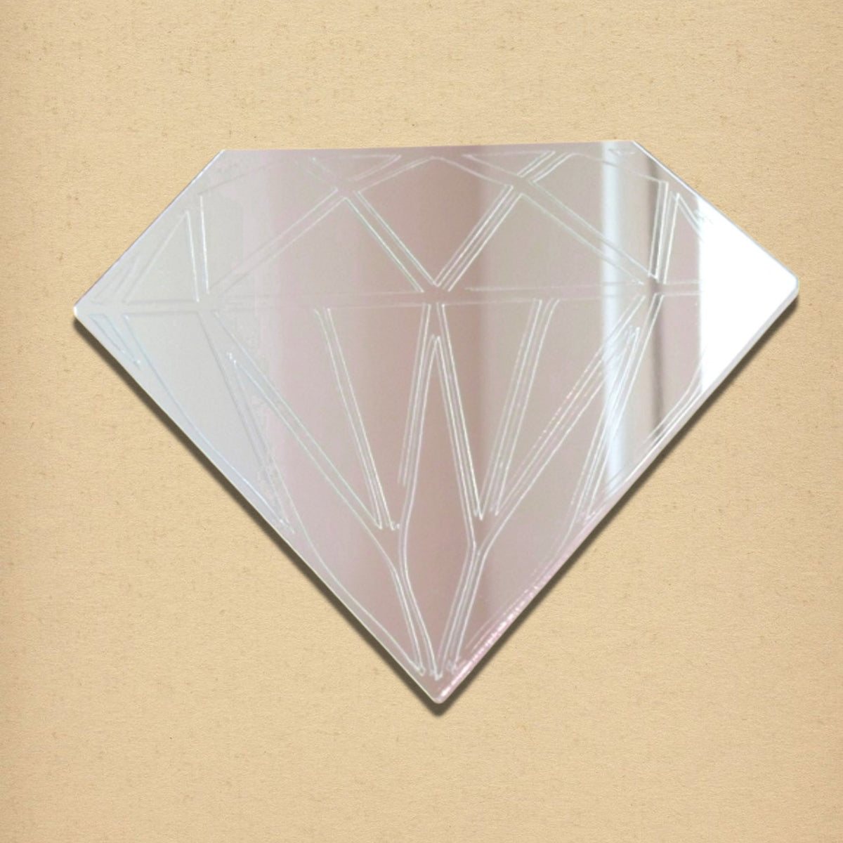 Diamond-shaped etched mirror with geometric facet lines on a light beige background.