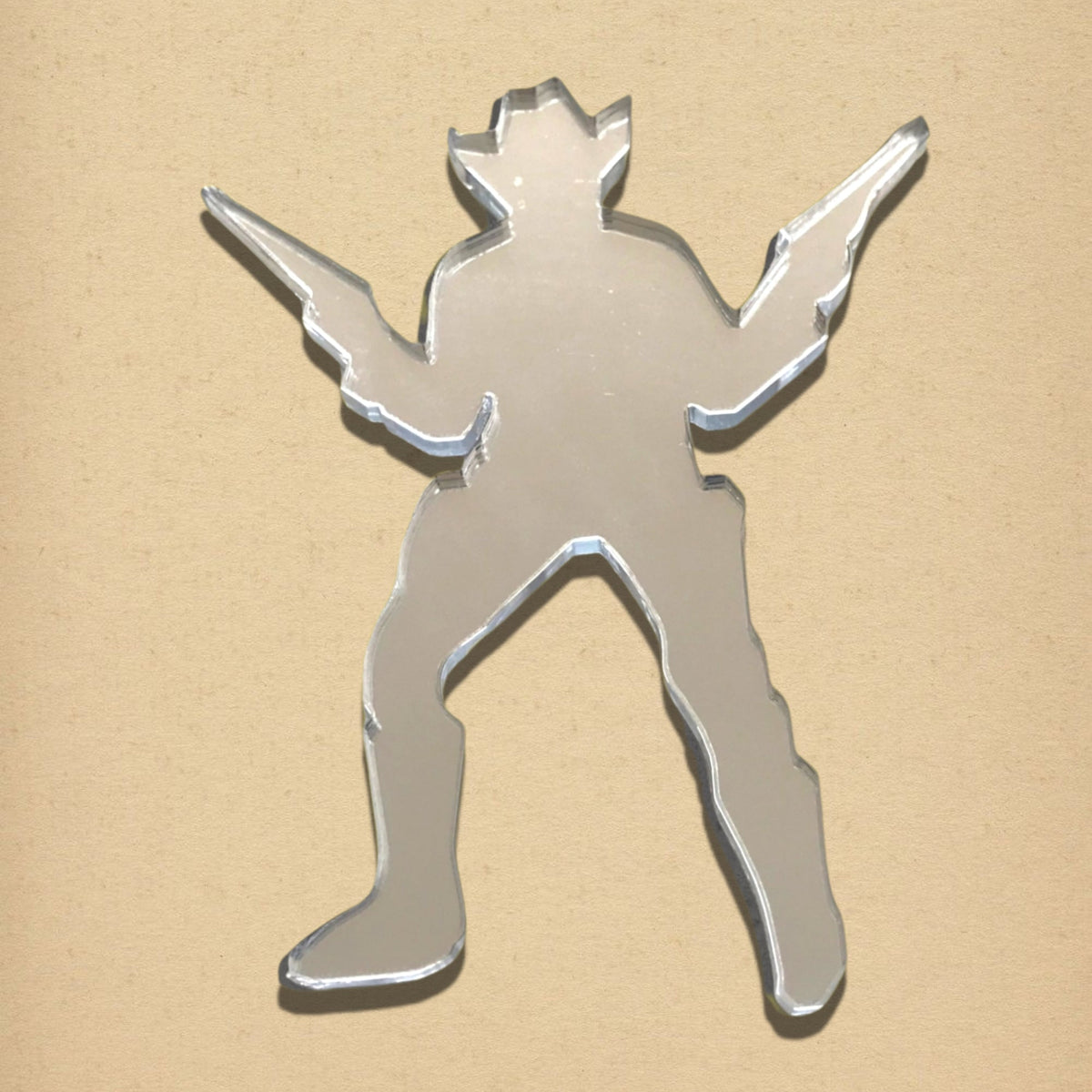 Cowboy-shaped mirror in a cowboy hat holding two guns against a tan background.