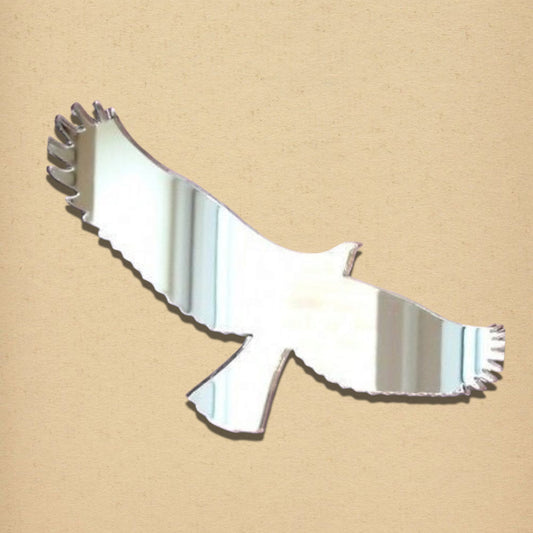 Eagle-shaped acrylic mirror in silver, displayed on a textured beige surface.