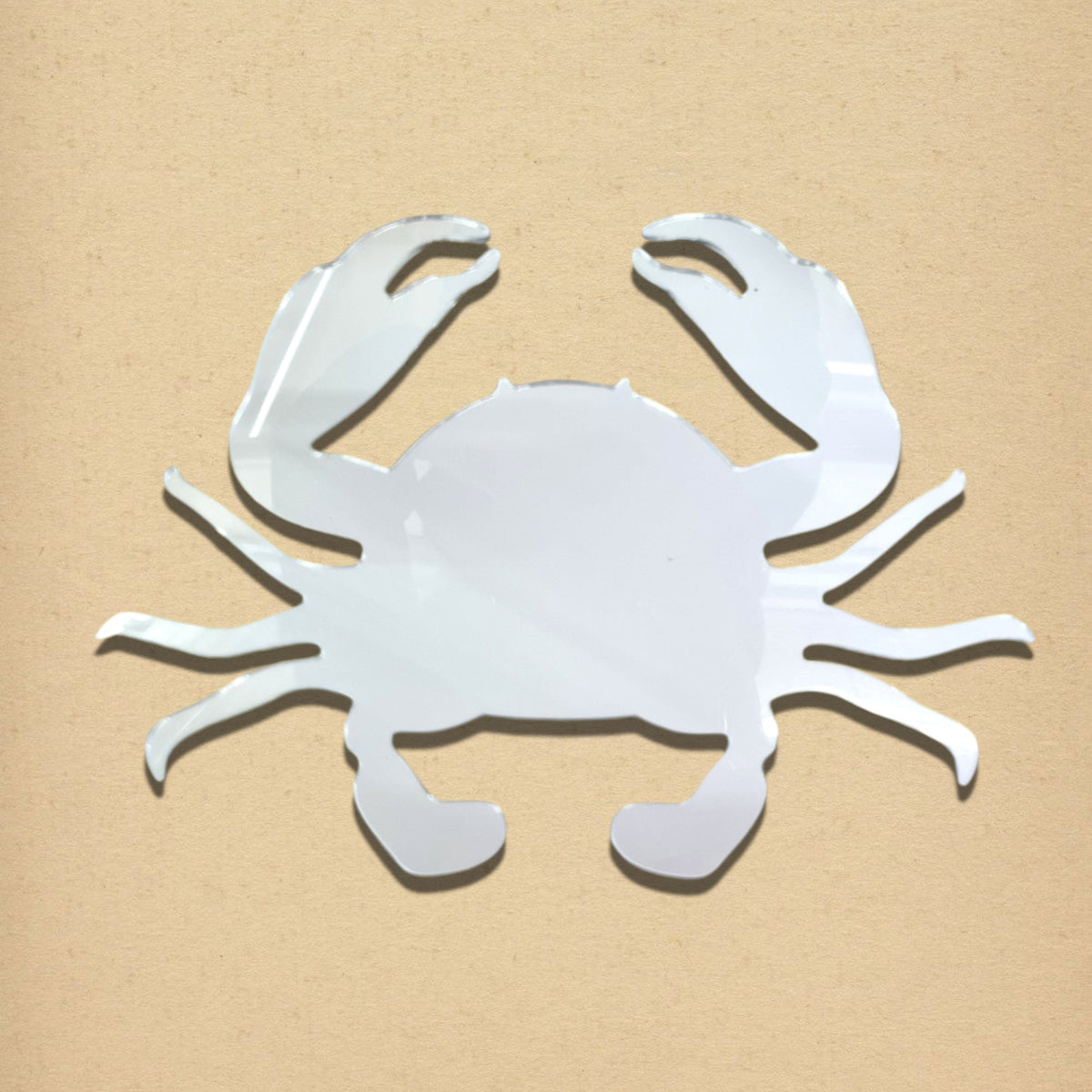 Silver crab-shaped mirror on a light brown background.