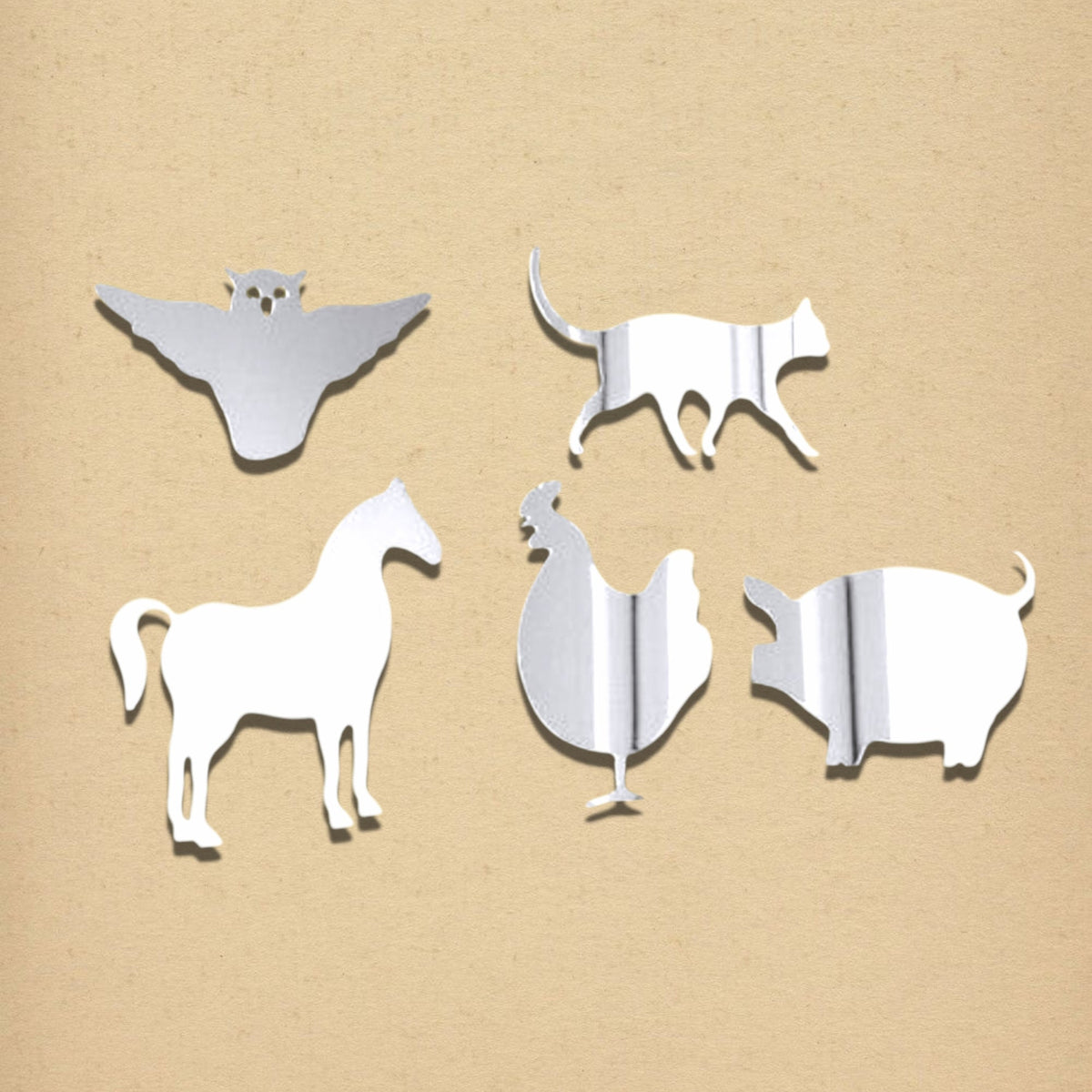 Four silver acrylic mirrors shaped like farm animals: an owl, cat, horse, rooster, and pig against a tan background.