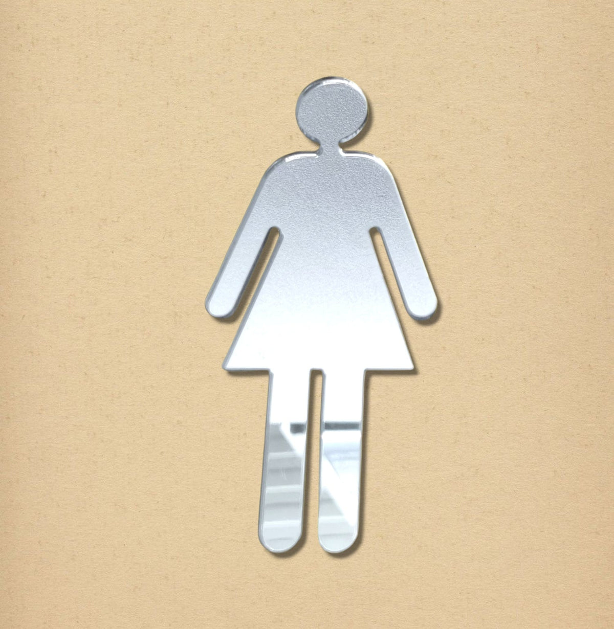 Mirrored female toilet sign in the shape of a woman in a dress against a beige background.
