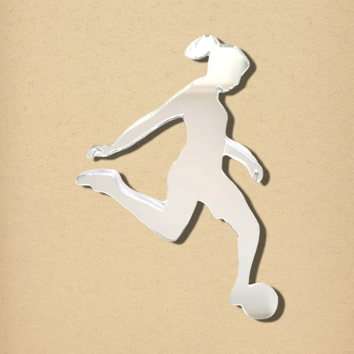 Female footballer silhouette mirror made of reflective acrylic on a beige background.