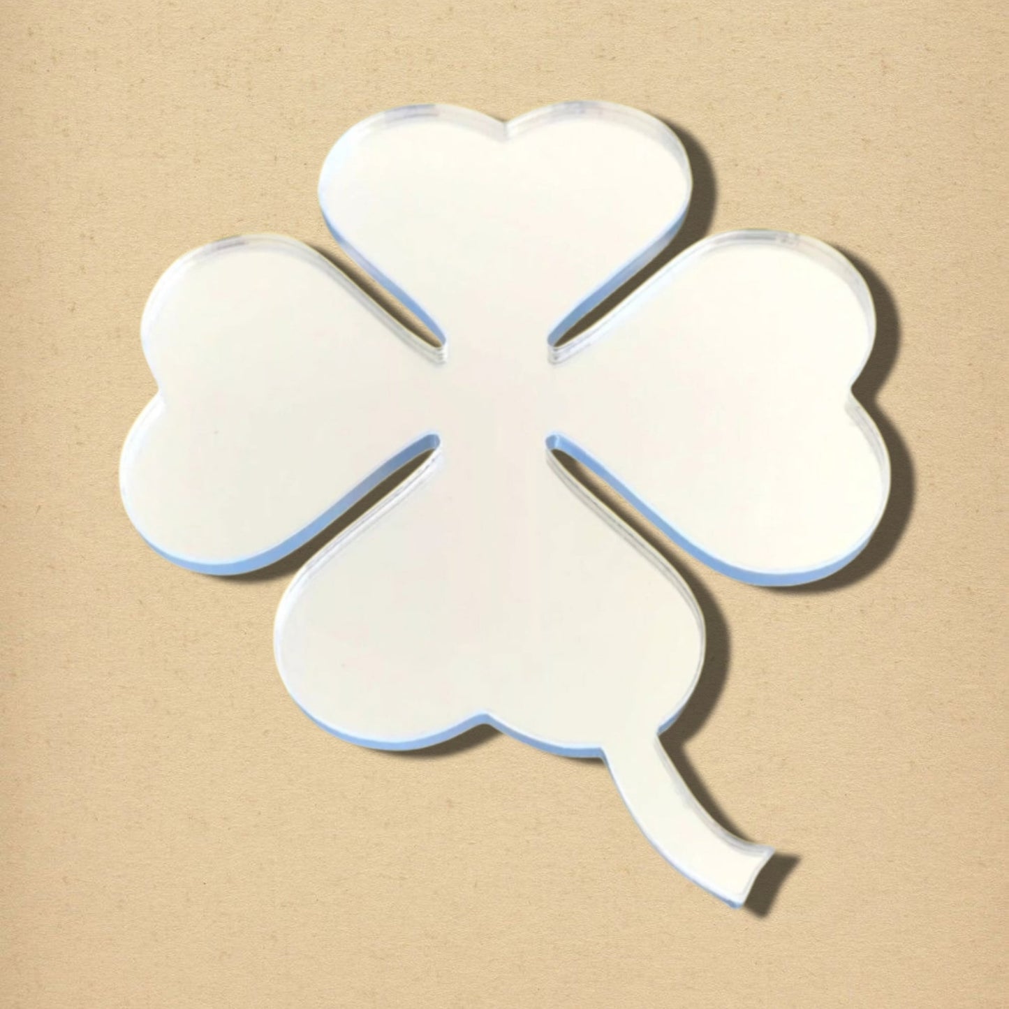 Four-leaf clover-shaped acrylic mirror with a short stem, set against a plain beige background.