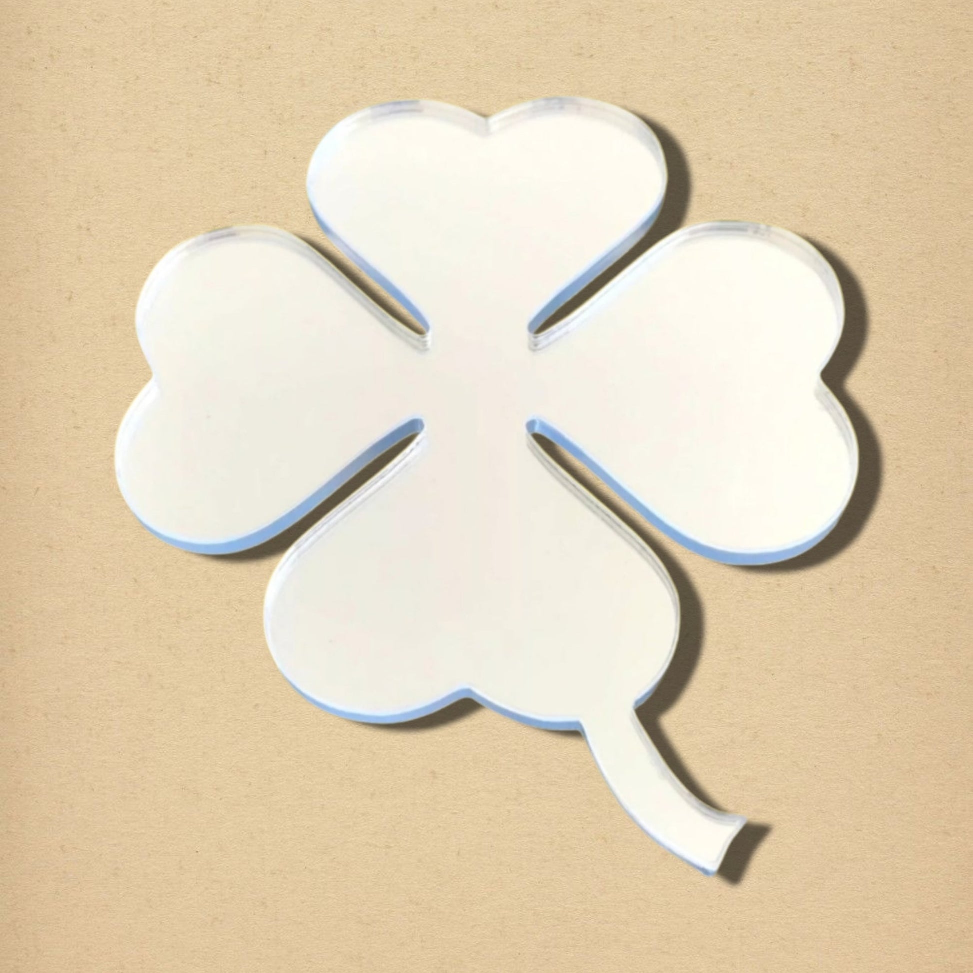 Four-leaf clover-shaped acrylic mirror with a short stem, set against a plain beige background.