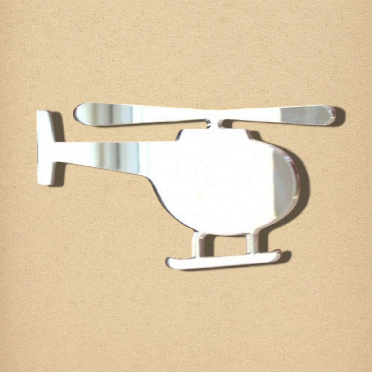 Helicopter-shaped reflective mirror with rotor blades and landing skids on a neutral background.