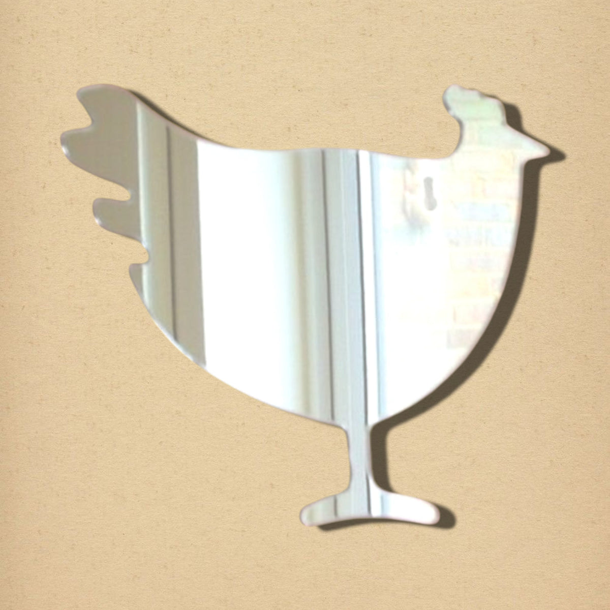 Hen-shaped reflective mirror on a tan background.
