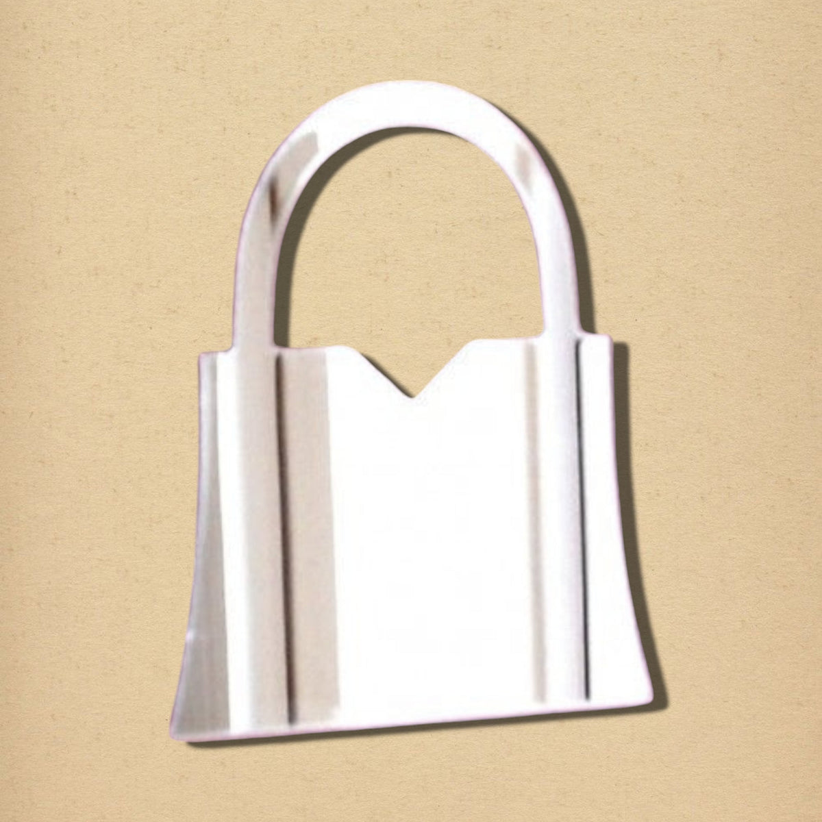 Handbag-shaped silver mirror with an arched handle on a beige background.