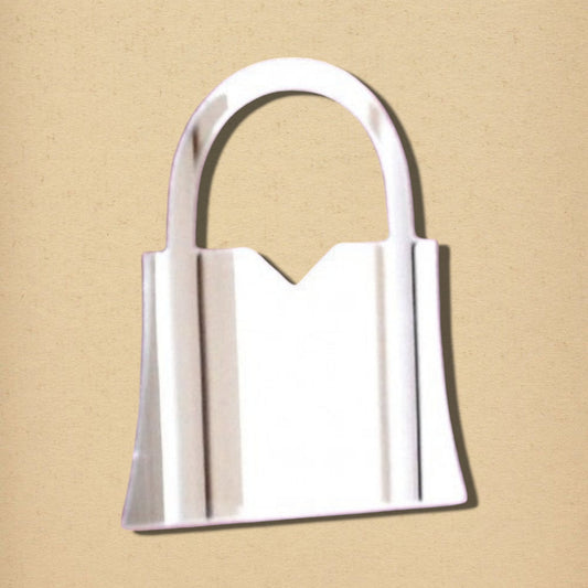 Handbag-shaped silver mirror with an arched handle on a beige background.