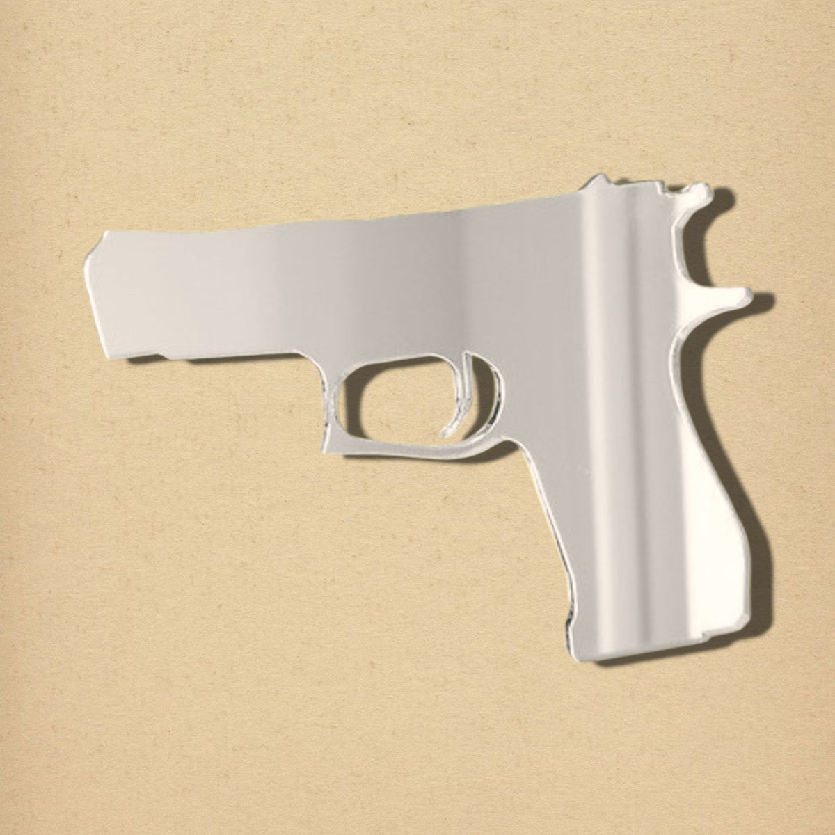 A handgun-shaped silver mirror on a light tan background.