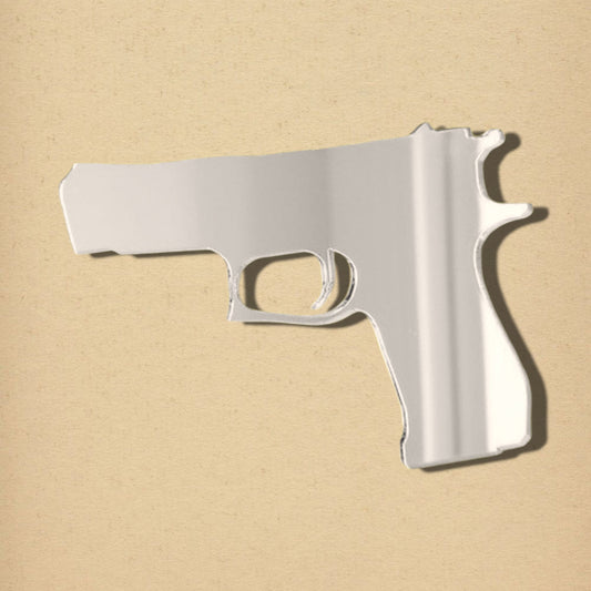 A handgun-shaped silver mirror on a light tan background.