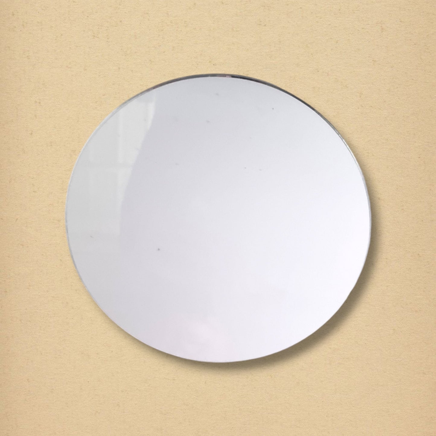 Simple round glass circle mirror against a solid beige background.