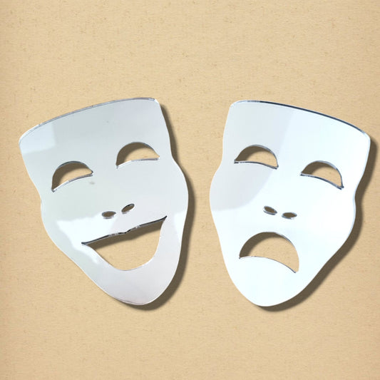 Two mirror theatre masks, one smiling comedy mask and one frowning tragedy mask, on a neutral beige background.