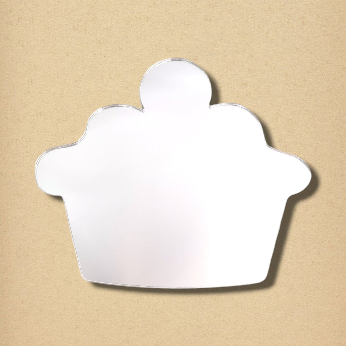 A cupcake-shaped wall mirror with a cherry topper on a tan background.